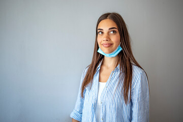 Woman wearing medical protective mask below the chin, wrong way to use protective mask. Covid-19. Portrait of woman wearing surgical mask on chin. Masking policy concept.