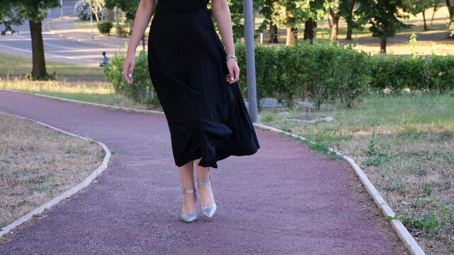 legs of young attractive woman walking at park with her dress blown by the wind