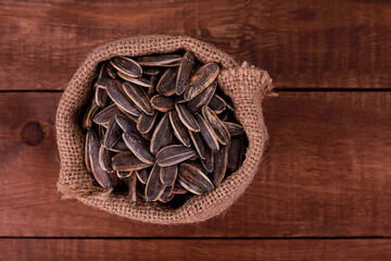 Sack of sunflower seeds on brown wooden table. Top view, closeup, copy space. Food, harvest, farming, agriculture concept