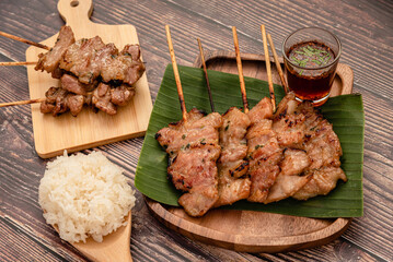 Thai traditional grilled pork and steamed sticky rice on wooden background 