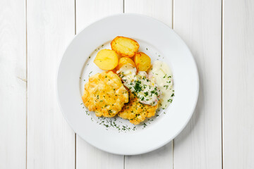 Top view of ground chicken meat cutlet with fried potato wedges and creamy sauce with bacon