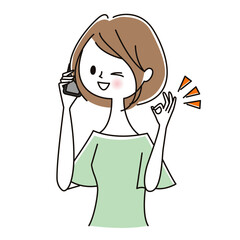 スマホで話しながらOKサインを出す女性