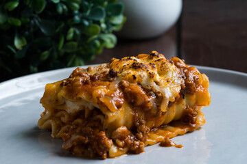 an Italian dish made of stacked layers of flat pasta, ground beef tomato sauce, cream and cheese also known as lasagna