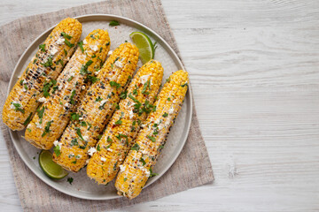 Homemade Elote Mexican Street Corn on a plate on a white wooden background, top view. Flat lay, overhead, from above. Space for text.