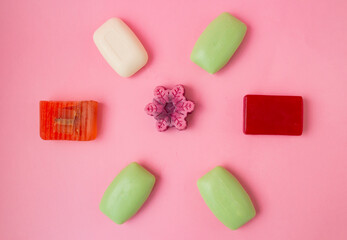 seven different types of soap on a pink background, top view