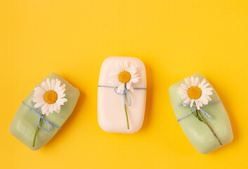 Fototapeta na wymiar Set of natural handmade soap, decorated with white chamomile flowers on a yellow background. Organic cosmetics, zero waste, environmentally friendly concepts. Top view Flat lay.