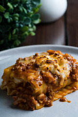 an Italian dish made of stacked layers of flat pasta, ground beef tomato sauce, cream and cheese also known as lasagna