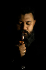Royal looking man with long beard lighting a cigarette