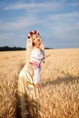 Young european woman with long blond hair in a white dress in a wheat field