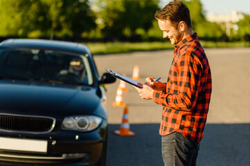 Male instructor and woman in car, traffic cones