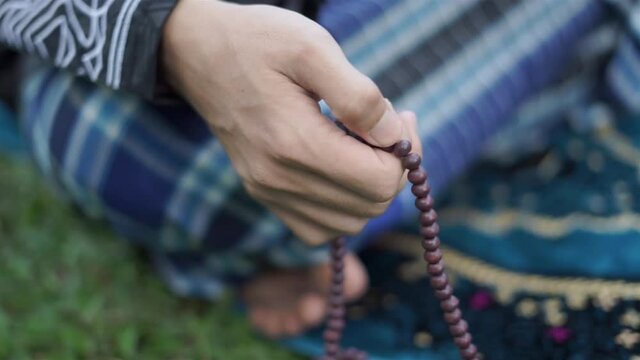 Muslim man praying with Islamic beads in hand, religious meditation, worship