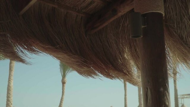 Tratch roof of bamboo hut on the tropical beach moving from wind, 4k slow motion