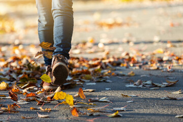 A woman walks through the autumn foliage. Close-up of legs