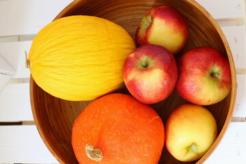 Bambus Schüssel mit Obst und Gemüse bestehend aus Äpfeln, Kürbis und Melone auf weißer Holzkiste