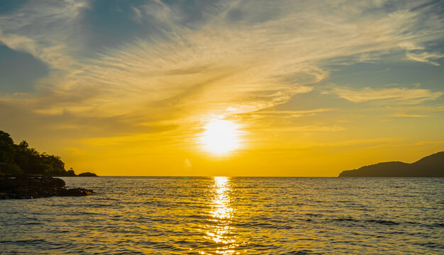 Front view in the indigo blue ocean in the evening, the sun was setting, reflections fell on the smooth calm surface with golden warm light. The sky is clear and clean. Feeling refreshed and relaxed. 