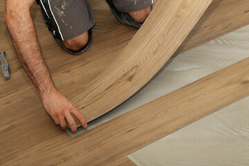 The worker installing new vinyl tile floor