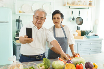 Asian Elderly couple learning how to cook online using a smartphone.