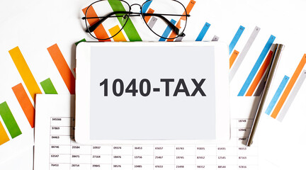 The tablet with text 1040-TAX on business charts and pen