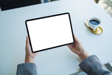 Mockup image of a woman holding digital tablet with blank white desktop screen in the office