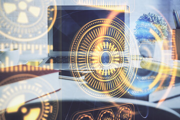 Computer on desktop in office with technology theme hologram. Double exposure. Tech concept.