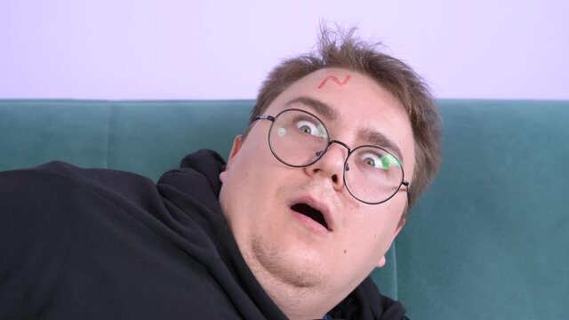 Close up portrait of sleeping young plump male with short hair cut, wearing eyeglasses, with lightening on forehead. Suddently he wakes up and makes exaggeratedly frightened face expression