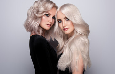 Two beautiful girls with hair coloring in blond. Stylish hairstyle curls done in a beauty salon. Beauty, cosmetics and makeup