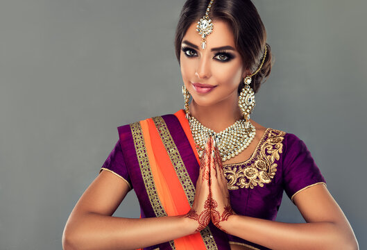 Portrait of a beautiful indian girl in a greetting pose to Namaste .India woman in traditional sari dress and jewelry.
