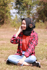 Fashion portrait of young beautiful asian muslim woman listening the music.