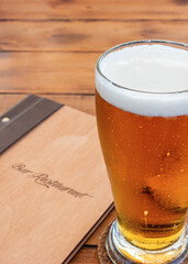 Glass of beer and a menu on a wooden table