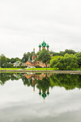 Fototapeta na wymiar Church of the life-giving Trinity in Ostankino in Moscow Russia on the Bank of a pond and reflection in the water on a cloudy summer day among green trees and copy space