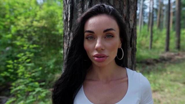 Woman standing against a tree and looking straight at the camera
