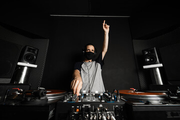 Disk jockey pinchando música usando mascarilla contra el coronavirus covid 19 para mantener la...