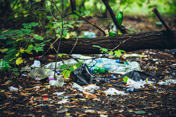 Garbage pile in forest among plants. Toxic plastic into nature everywhere. Rubbish heap in park among vegetation. Contaminated soil. Environmental pollution. Ecological issue. Throw trash anywhere.