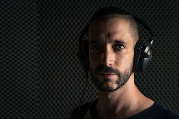 Hombre con peinado moderno y ojos azules, y camiseta gris de mangas azul marino con auriculares en...