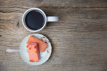 top view of black coffee in white cup on wood plank with nice texture, sweet in plate, concept of coffee break and snack