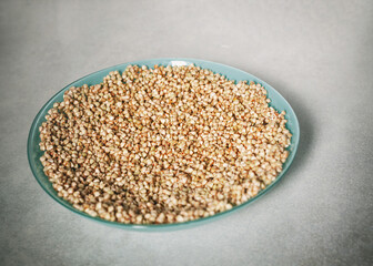Healthy Food Background. Plate of green buckwheat on a background of light gray stone table. Soaked buckwheat and grains are ready for germination. 