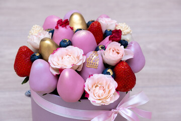 Fresh strawberries in pink, gold and white chocolate with pink flowers in the form of a fruit bouquet.