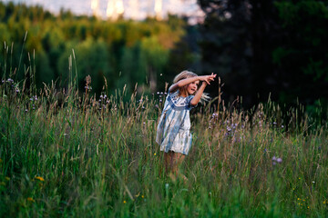 A girl chasing a butterfly in a flower meadow.  Shot at Holmenkollen, Oslo, Norway.
