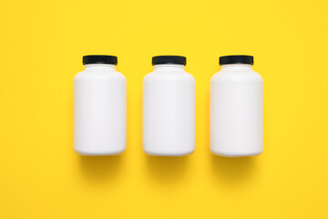 White plastic jars on the yellow flat lay background.
