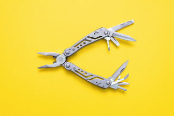 Steel multi tool on the yellow flat lay background. - obrazy, fototapety, plakaty
