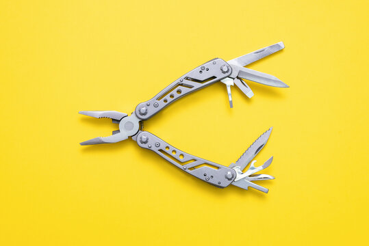 Steel multi tool on the yellow flat lay background.