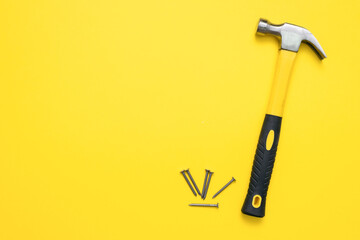 Hammer and heap of nails on the yellow flat lay background with copy space.
