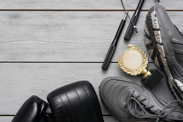Boxing gloves, sneakers, jumping rope and golden award trophy on the wooden floor flat lay...