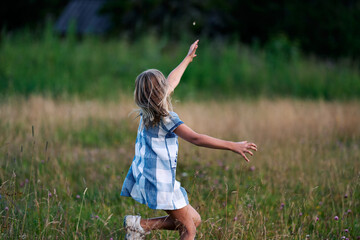 Naklejka na ściany i meble A girl chasing a butterfly in a flower meadow. Shot at Holmenkollen, Oslo, Norway.