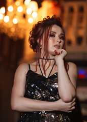 Young woman with red hair in a fashion dress in a cafe or restaurant