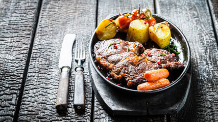 Roasted steak with vegetables on burned table