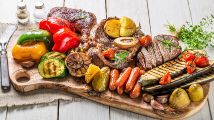 Grilled vegetables and meat with herbs on white table