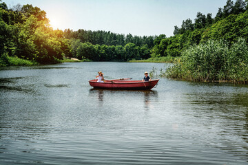 Children travel by boat. A boy and a girl are fishing. Children in a boat sail on the river

