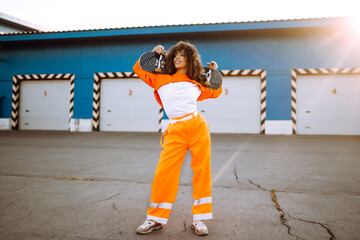 Beautiful African  American woman posing with a skateboard. Hipster girl with curly hair with...