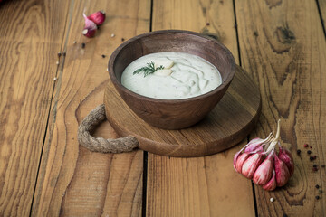 Garlic sauce with dill in a wooden bowl on a wooden table